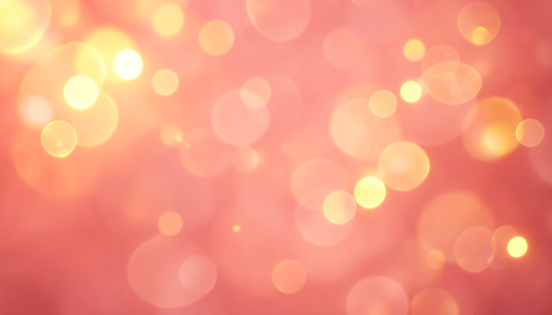 Warm golden light with soft bokeh circles on a rose-tinted background, festive and hopeful mood